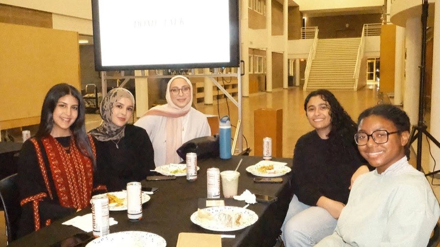 Members share an iftar meal at a long table during the Dome Talk