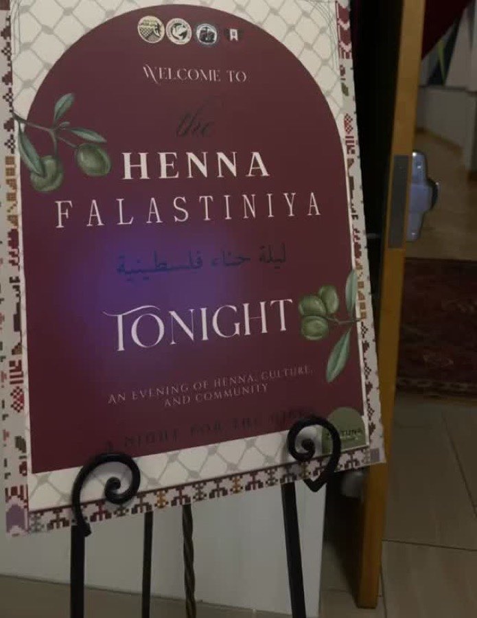 Welcome sign for Henna Falastiniya on an easel, framed by tatreez and keffiyeh patterns
